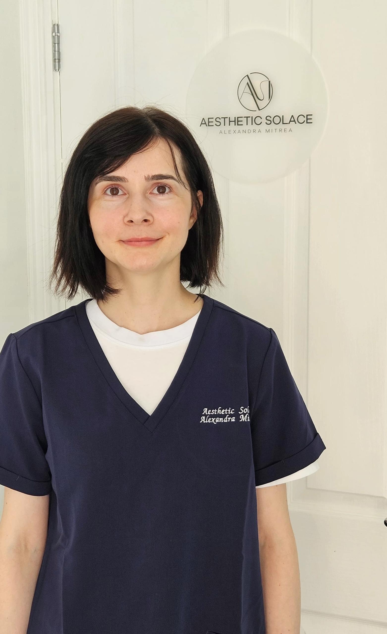 Aesthetic Practitioner Alexandra Mitrea wearing the branded Aesthetic Solace scrubs and smiling friendly.